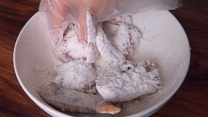 Cánh gà sau khi ướp xong thì lăn qua bột chiên giòn, đảo cho bột áo đều một lớp bên ngoài thịt gà.